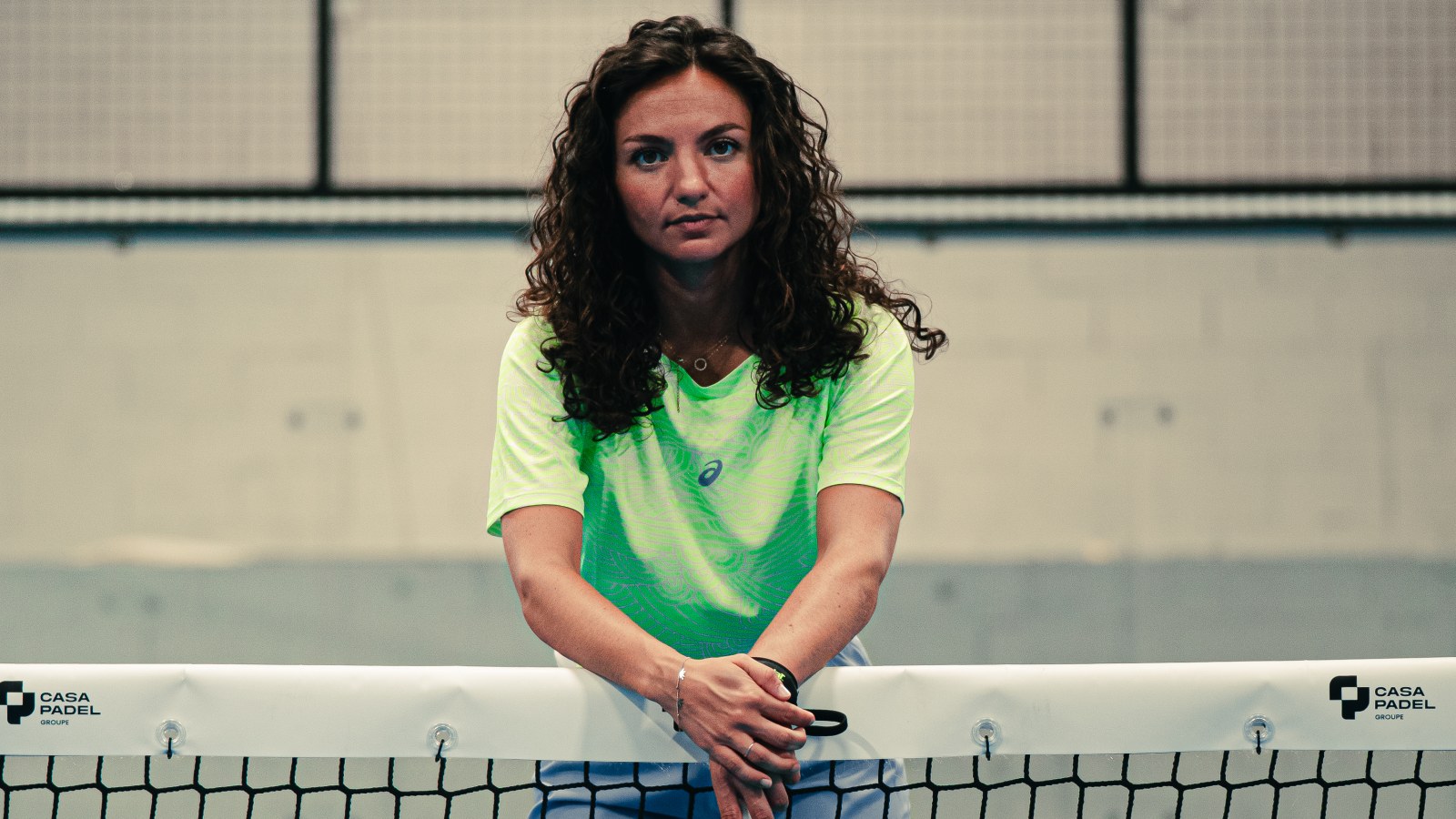 Asics — joueuse de padel appuyée sur le filet